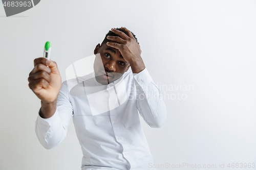 Image of Young unhappy african american man looking at pregnancy test. Handsome sad man frustrated and having problems. Guy depressed because of result of pregnancy test