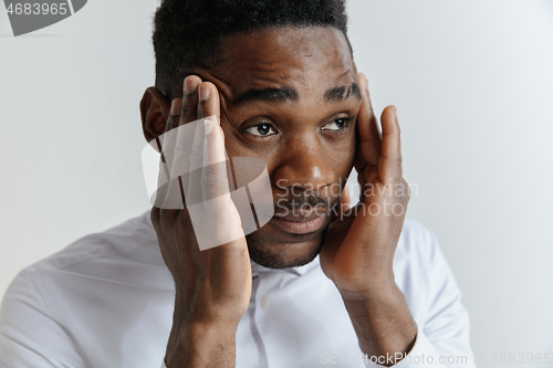 Image of Stressed young african american man having terrible strong headache.