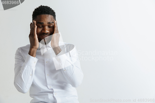 Image of Stressed young african american man having terrible strong headache.