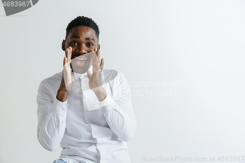 Image of Wow. Attractive male half-length front portrait on grey studio backgroud. Young afro emotional surprised bearded man standing with open mouth. Human emotions, facial expression concept.