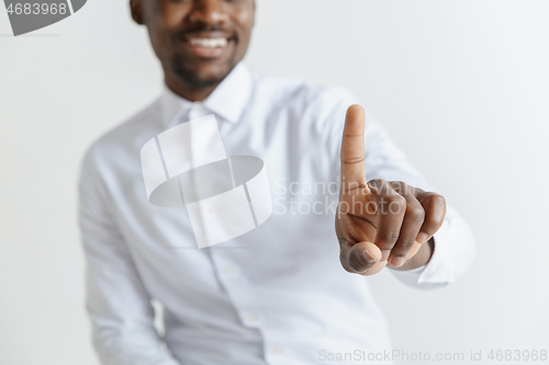 Image of Young african american guy interacts with empty space. Negative space to insert your text or image.