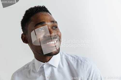 Image of Close up portrait of a happy young african american man laughing against gray background.