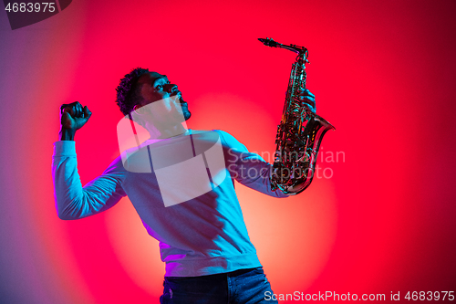 Image of African American handsome jazz musician interacts with audience and holding the saxophone.