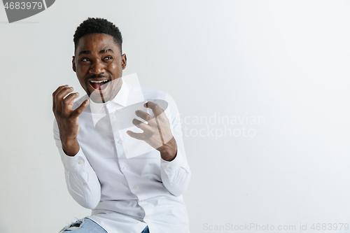 Image of Wow. Attractive male half-length front portrait on grey studio backgroud. Young afro emotional surprised bearded man standing with open mouth. Human emotions, facial expression concept.