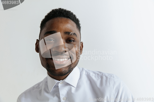 Image of Close up portrait of a happy young african american man laughing against gray background.