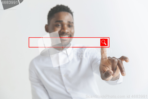 Image of Young african american guy interacts with empty search bar. Negative space to insert your text.