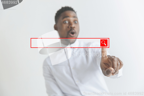 Image of Young african american guy interacts with empty search bar. Negative space to insert your text.