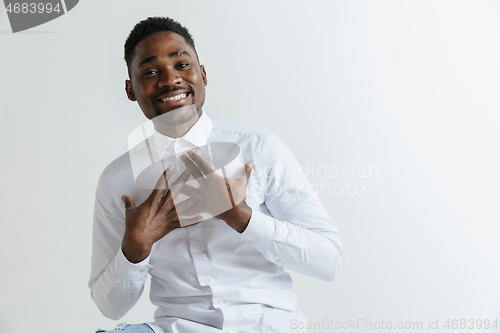 Image of Grateful happy pleased african man holding hands on chest.