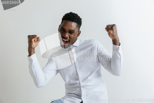 Image of Wow. Attractive male half-length front portrait on grey studio backgroud. Young afro emotional surprised bearded man standing with open mouth. Human emotions, facial expression concept.