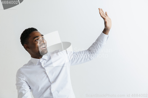 Image of Close up portrait of a happy young african american man laughing against gray background.
