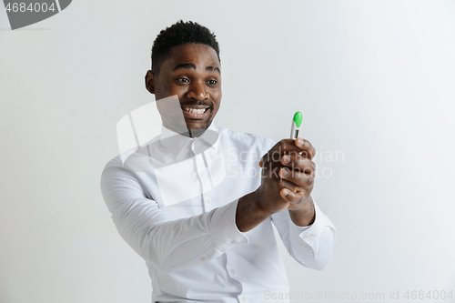 Image of Young happy african american man looking at pregnancy test. Handsome smiling man inspired and delighted. Guy pleased because of result of pregnancy test.