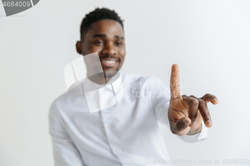 Image of Young african american guy interacts with empty space. Negative space to insert your text or image.