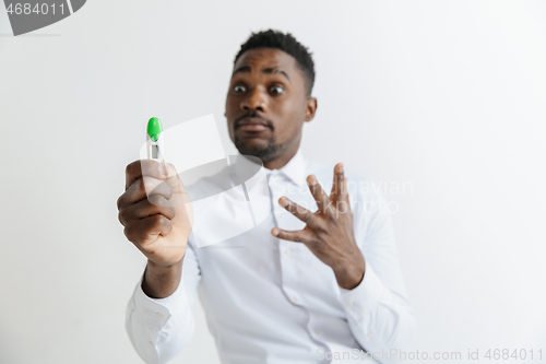 Image of Young unhappy african american man looking at pregnancy test. Handsome sad man frustrated and having problems. Guy depressed because of result of pregnancy test