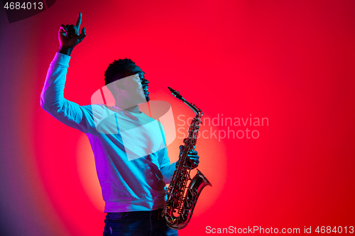 Image of African American handsome jazz musician interacts with audience and holding the saxophone.