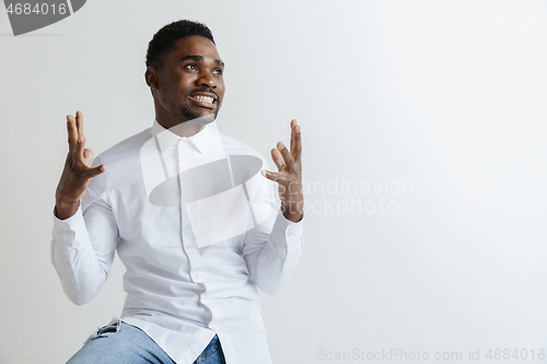 Image of Close up portrait of a happy young african american man laughing against gray background.