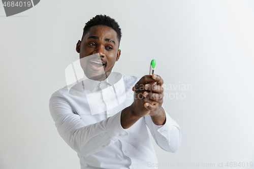 Image of Young happy african american man looking at pregnancy test. Handsome smiling man inspired and delighted. Guy pleased because of result of pregnancy test.