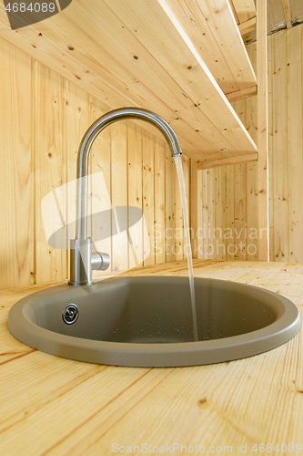 Image of In a kitchen made of natural wood, water flows from the mixer