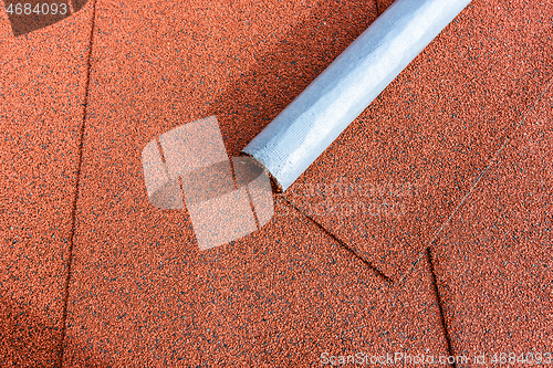 Image of There is a roll of red bituminous shingles on the tiled roof