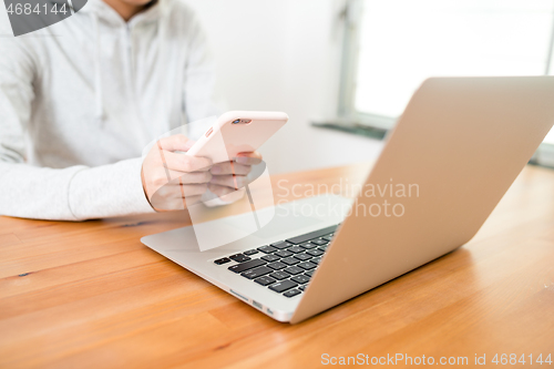 Image of Woman using laptop computer and cellphone at home