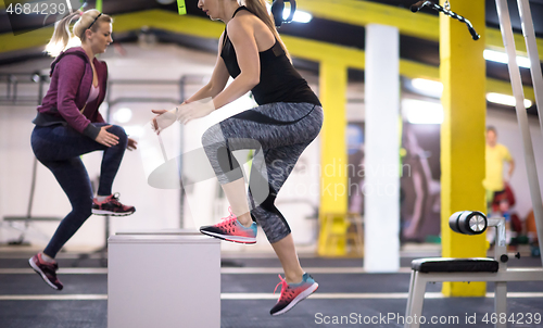 Image of athletes working out  jumping on fit box