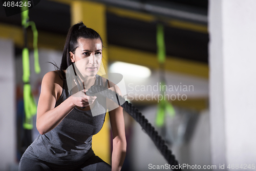 Image of athlete woman doing battle ropes cross fitness exercise