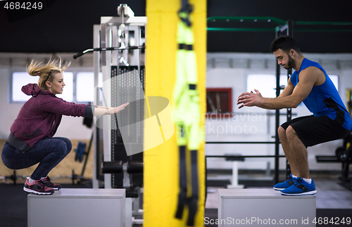 Image of athletes working out  jumping on fit box