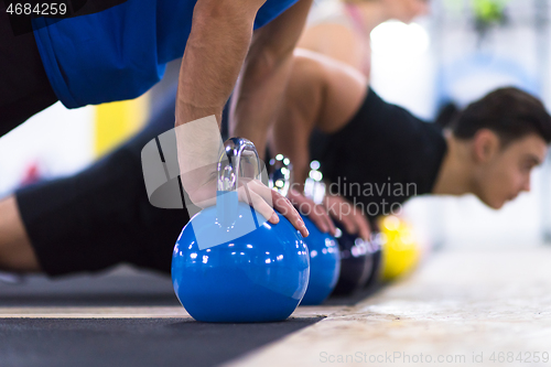 Image of young athletes doing pushups with kettlebells