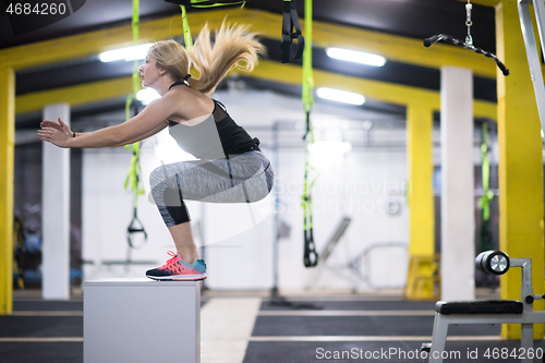 Image of woman working out  jumping on fit box