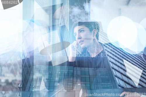 Image of Elegant Woman Using Mobile Phone by window in office building