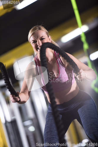 Image of athlete woman doing battle ropes cross fitness exercise