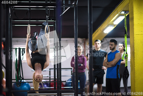 Image of woman working out with personal trainer on gymnastic rings