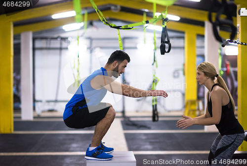 Image of woman working out with personal trainer jumping on fit box