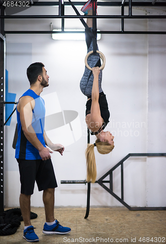 Image of woman working out with personal trainer on gymnastic rings