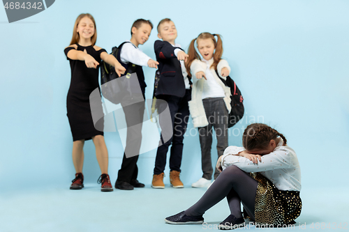 Image of Little girl sitting alone on floor and suffering an act of bullying.