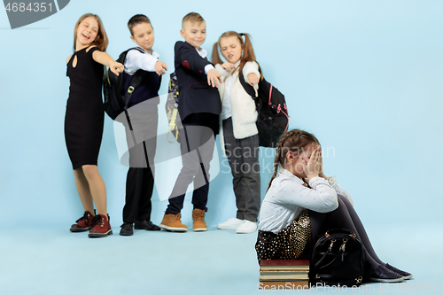 Image of Little girl sitting alone on floor and suffering an act of bullying.