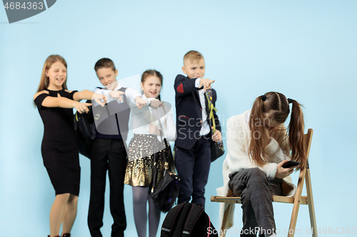 Image of Little girl sitting alone on chair and suffering an act of bullying.