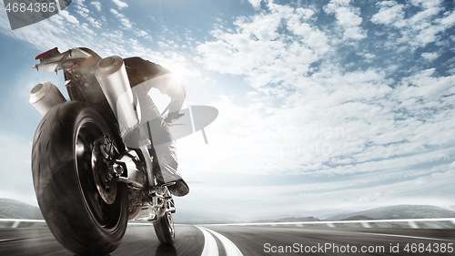 Image of Biiker on highway, riding around a curve with a motion blur toned