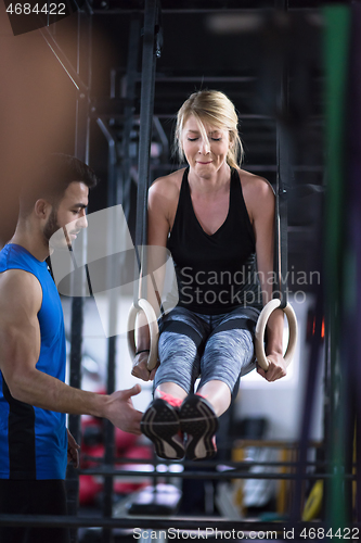 Image of woman working out with personal trainer on gymnastic rings