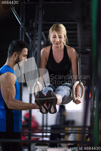 Image of woman working out with personal trainer on gymnastic rings