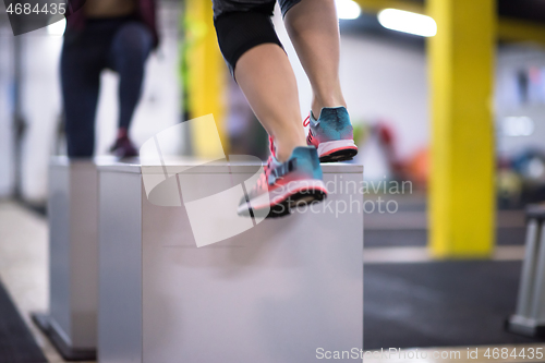 Image of athletes working out  jumping on fit box