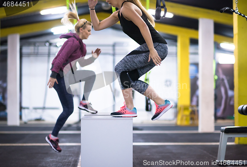 Image of athletes working out  jumping on fit box