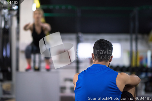 Image of woman working out with personal trainer jumping on fit box