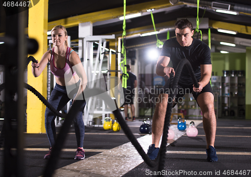 Image of sports couple doing battle ropes cross fitness exercise