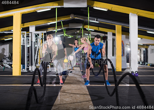 Image of sports couple doing battle ropes cross fitness exercise