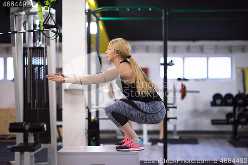 Image of woman working out  jumping on fit box