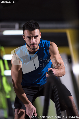 Image of athlete man doing battle ropes cross fitness exercise