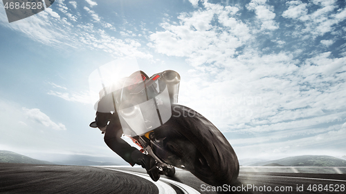 Image of Biiker on highway, riding around a curve with a motion blur toned