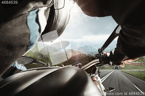 Image of Biiker on highway, riding around a curve with a motion blur toned