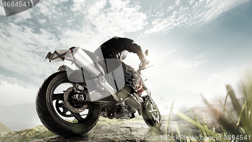 Image of Biiker on highway, riding around a curve with a motion blur toned