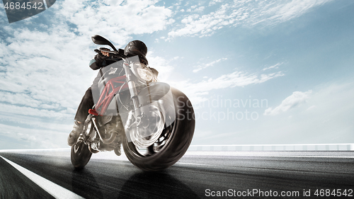 Image of Biiker on highway, riding around a curve with a motion blur toned